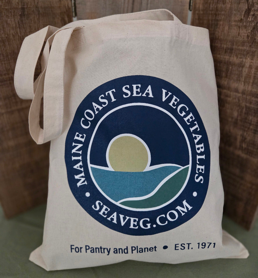 Beige tote bag with Maine Coast Sea Vegetables logo on a wooden surface
