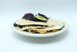 toasted quesadilla on a white plate with half an avocado and some red dulse